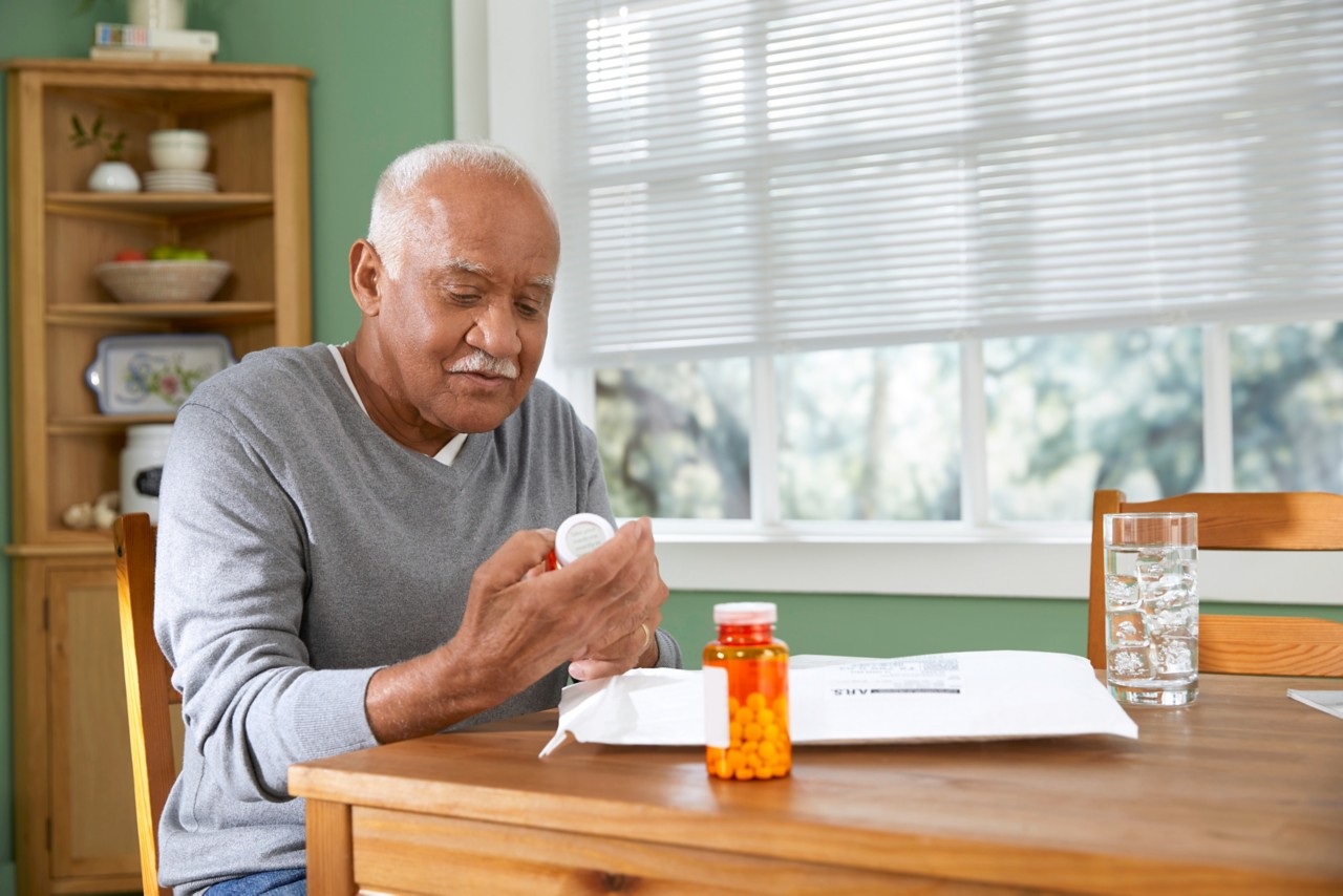Male member sitting in dining room reviews medication from non-cold pack